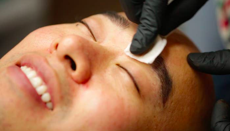 Close-up of a smiling man promoting Microblading for men.