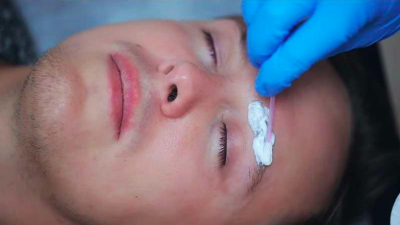A cosmetic artist applying numbing cream before the Microblading procedure.