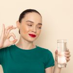 Front view of young woman smiling with a glass of water needed to protect your SPMU.
