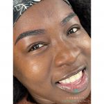 A black female client smiling after her eyebrow enhancement procedure.