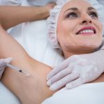 Cara injecting polynucleotide treatment in a client's armpit.