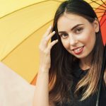 Young smiling woman holding a sun umbrella demonstrating how to protect your SMPU.