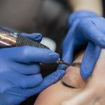 Cosmetic tattoo artist using the latest tool for eyebrow treatment.