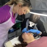 Cara looking on while a student performs SPMU treatment on a live model.